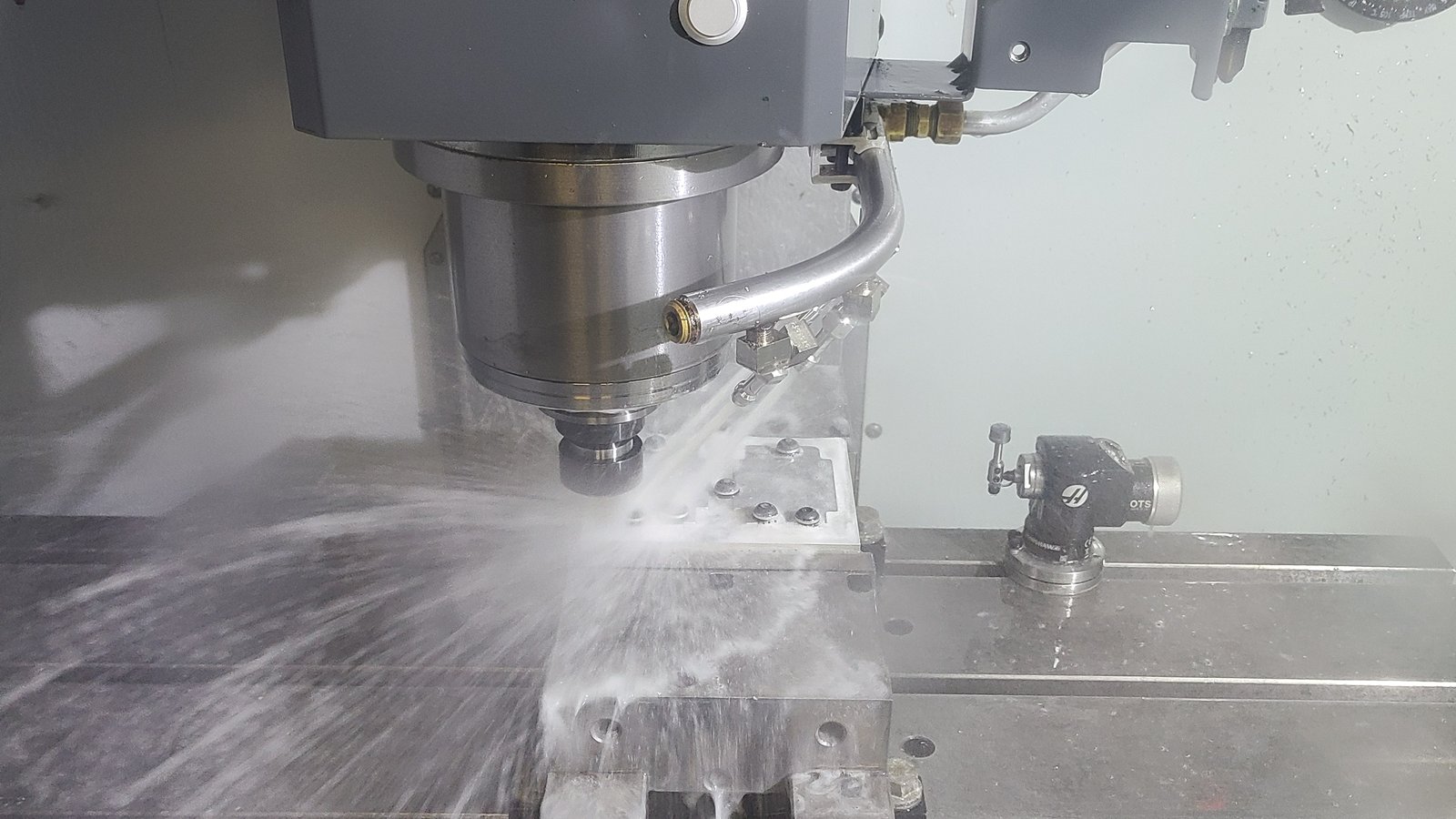 CNC mill cutting a part in the vise, coolant spraying
