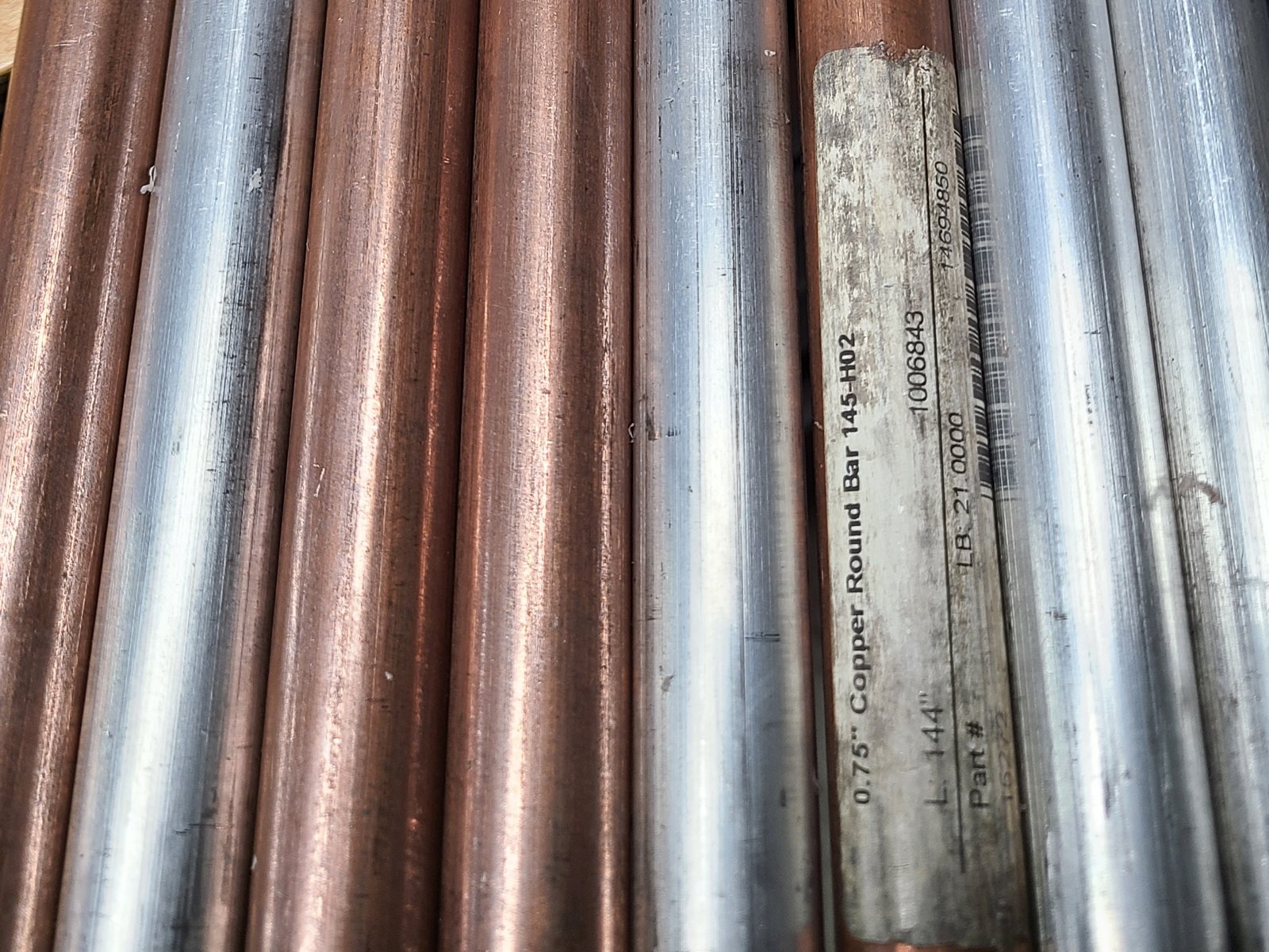 Copper and aluminum round bar stock, with a tag reading 0.75 inch copper round bar 145-H02